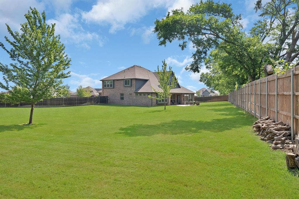 Expansive green lawn with mature trees and a private wooden perimeter fence