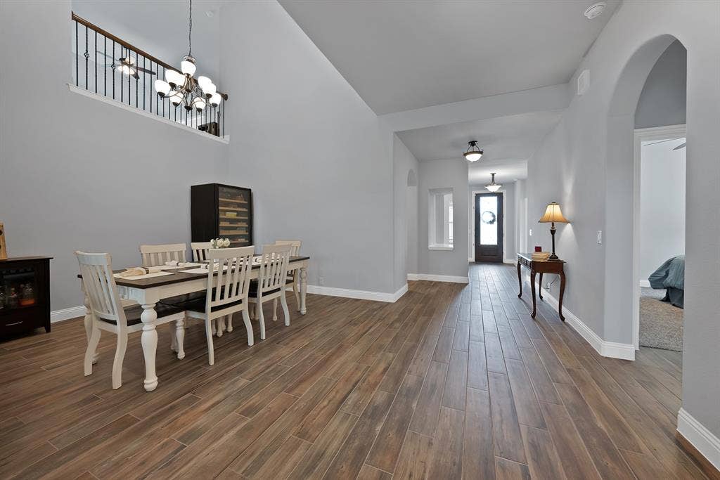 Expansive entry foyer and dining area featuring wood-finish flooring, high ceilings, and archway entries
