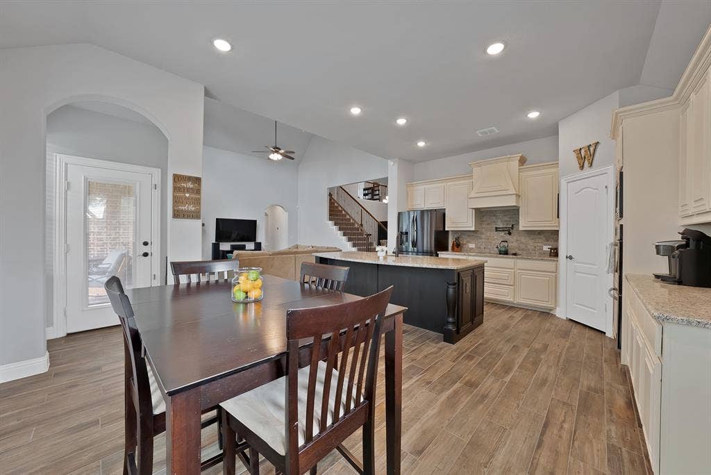 Open-concept kitchen and dining area featuring wood-look tile flooring, recessed lighting, and a kitchen island with seating