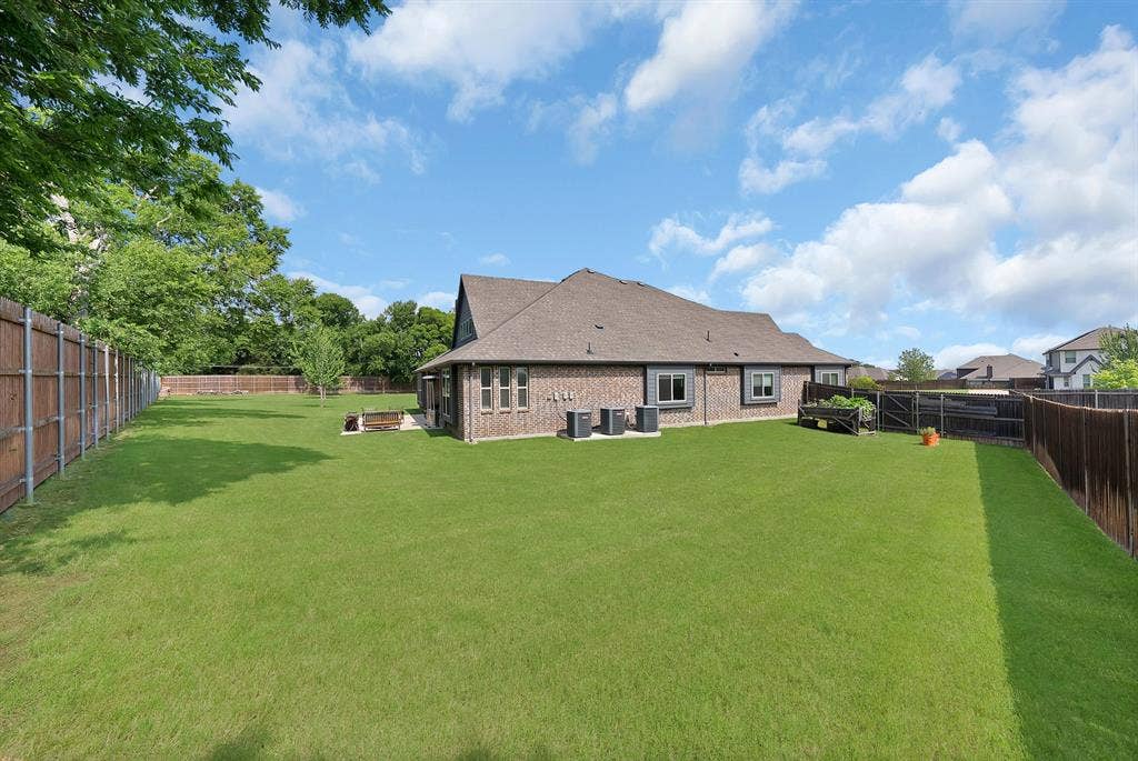Expansive green lawn with mature trees and a privacy fence