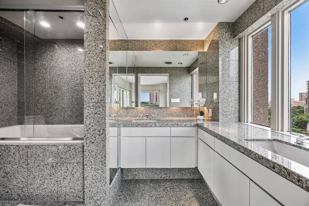 3030 Mckinney Avenue, #701, Dallas, TX 75204 Light-filled primary bath with dual vanities, and stone-clad finishes.