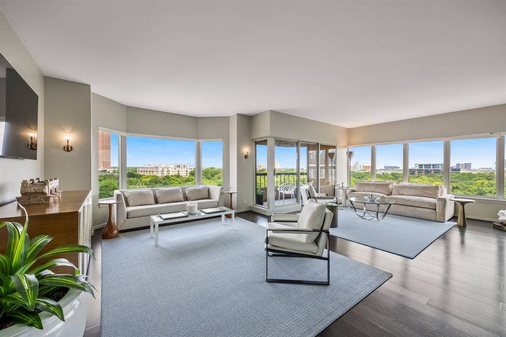 3030 Mckinney Avenue, #701, Dallas, TX 75204 Expansive living space framed by walls of windows, treetop views, and a city backdrop.