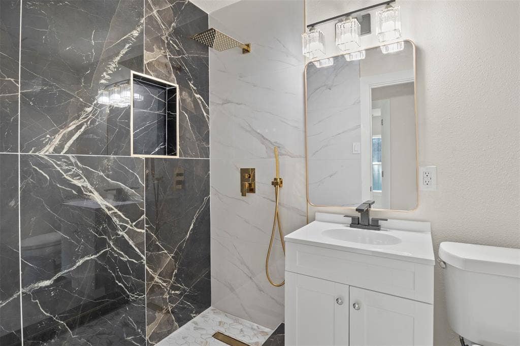 Contemporary bathroom featuring a walk-in shower with dark marbled wall tile and a built-in shower niche