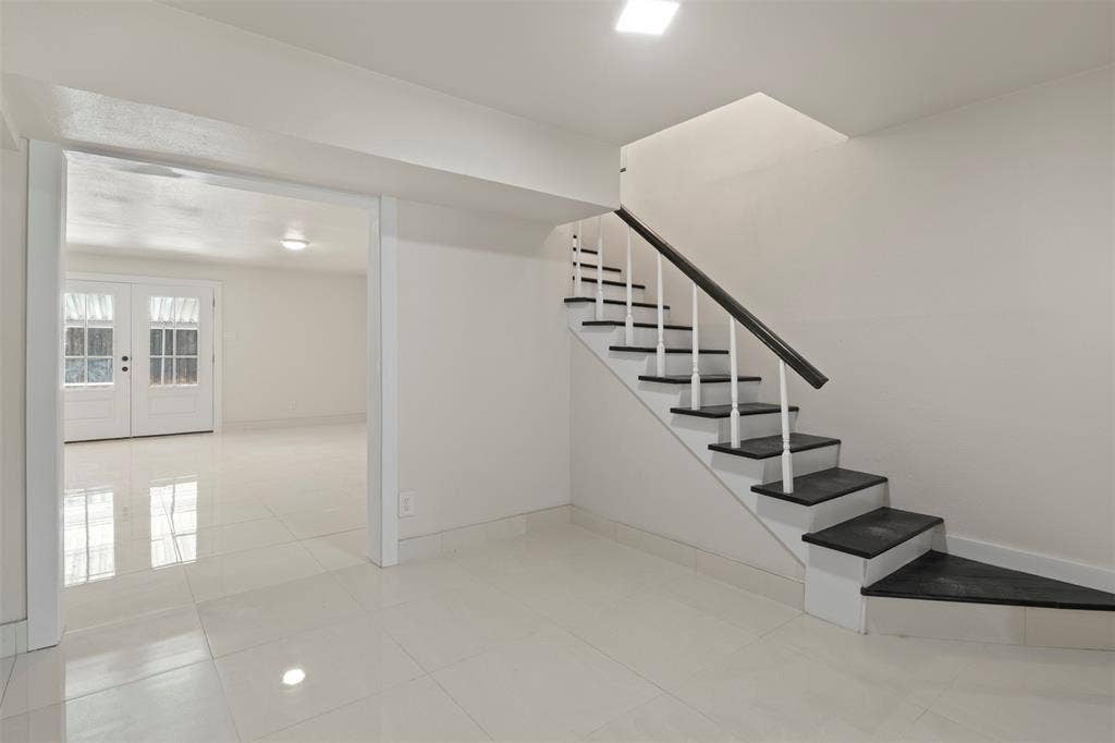 White interior with a prominent staircase featuring a dark handrail and white spindles