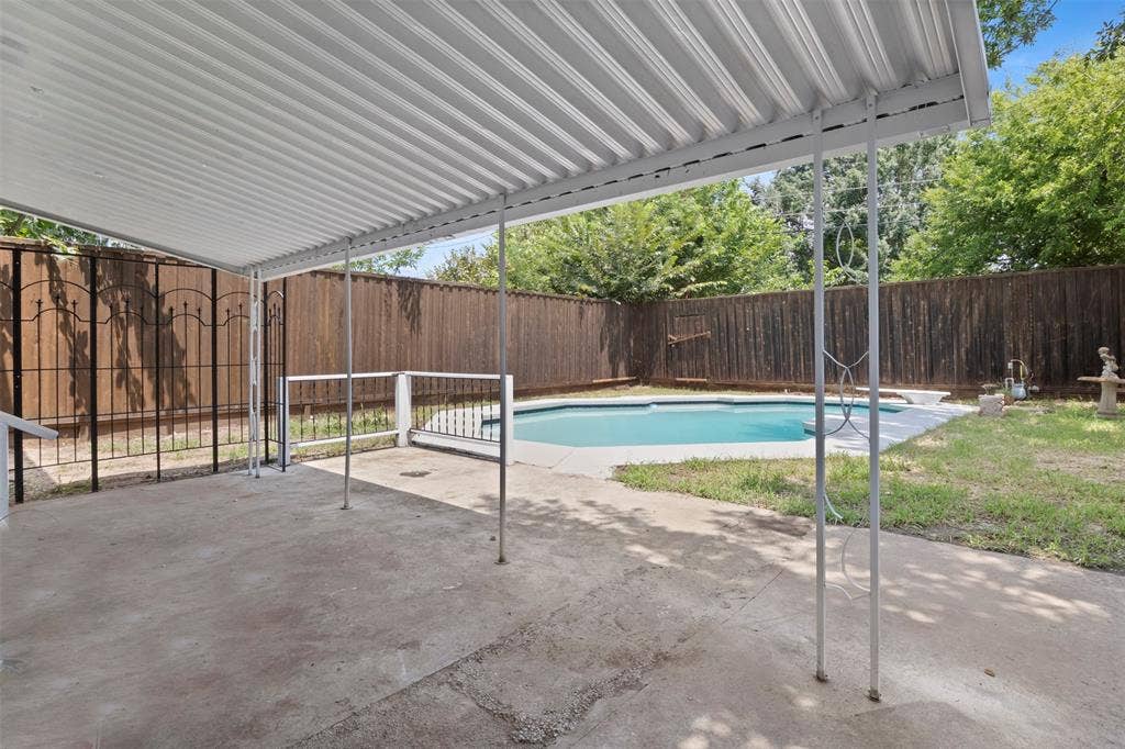 Covered patio space featuring a concrete slab, metal support columns, and a corrugated metal roof