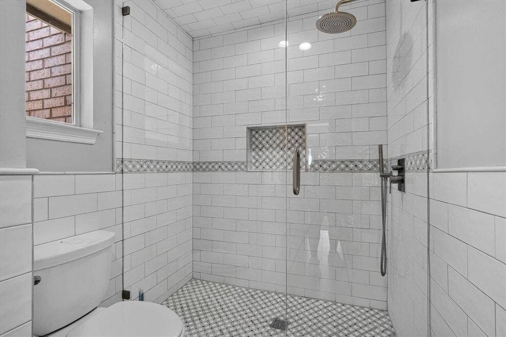 Glass-enclosed shower with subway tile walls, decorative accent band, and mosaic tile flooring