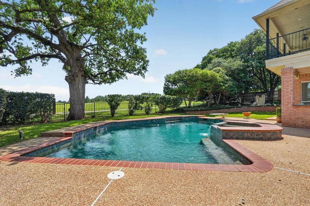 Outdoor swimming pool featuring a brick coping and an integrated spa with a waterfall feature