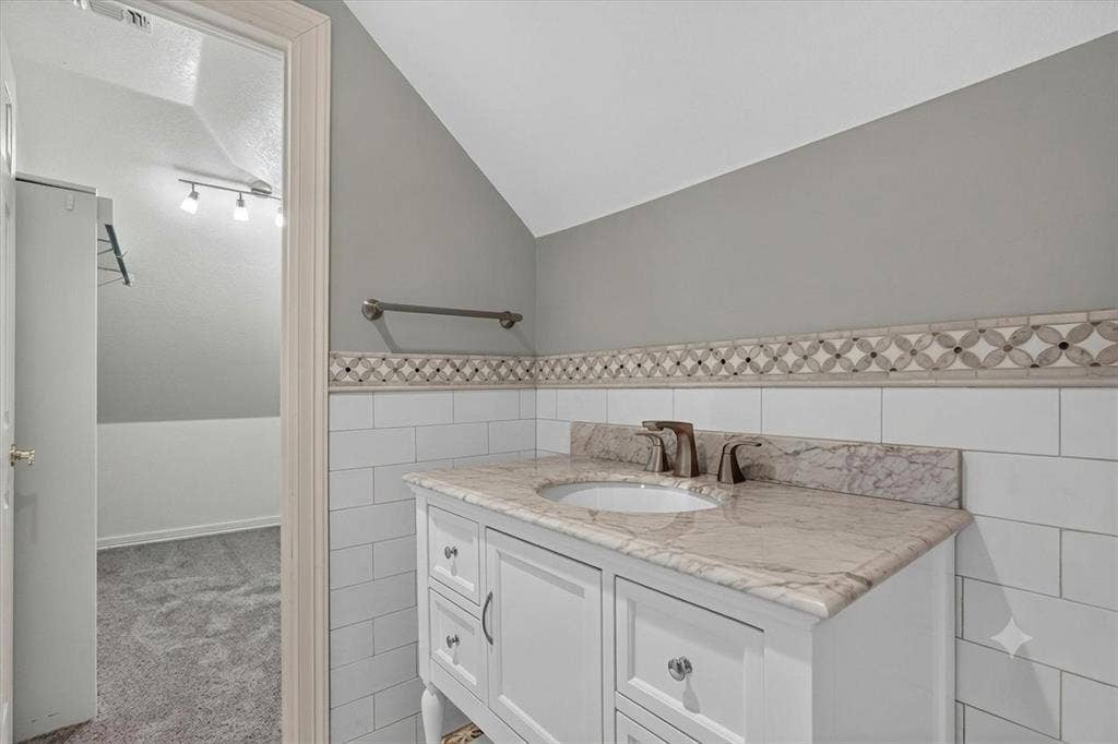 Vanity with a light-toned countertop, under-mount sink, and bronze-finish faucet