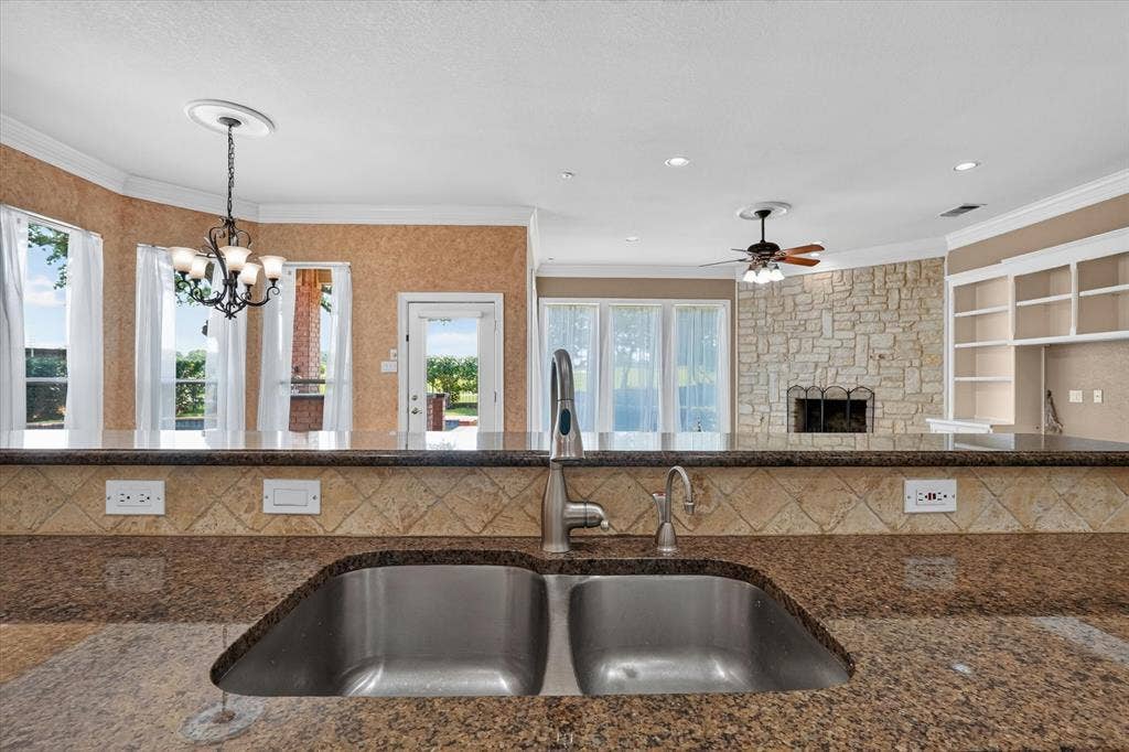 Kitchen featuring a double-basin stainless steel sink, granite countertops, and a tiled backsplash
