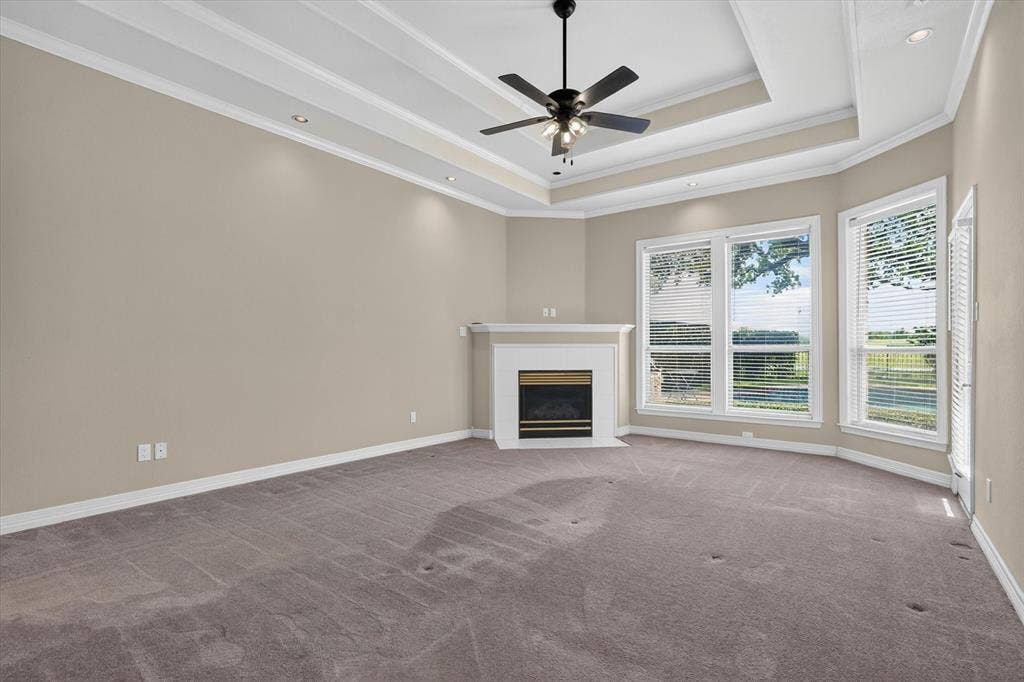 Expansive room featuring a tray ceiling with a black ceiling fan, recessed lighting, and a white fireplace mantel