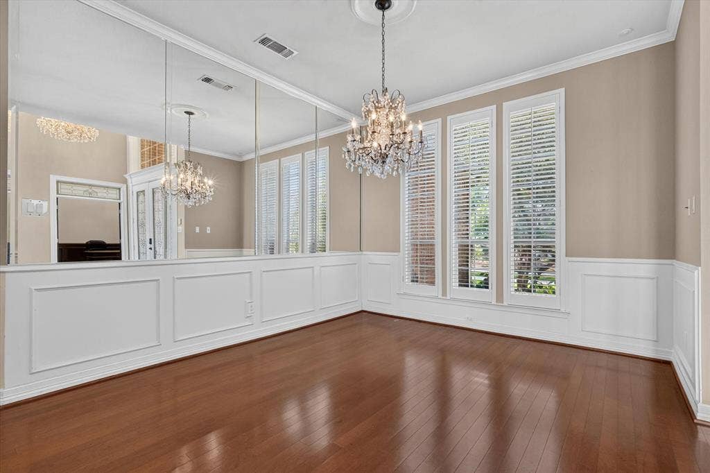 Room featuring wood-finish flooring, wainscoting, and a crystal chandelier