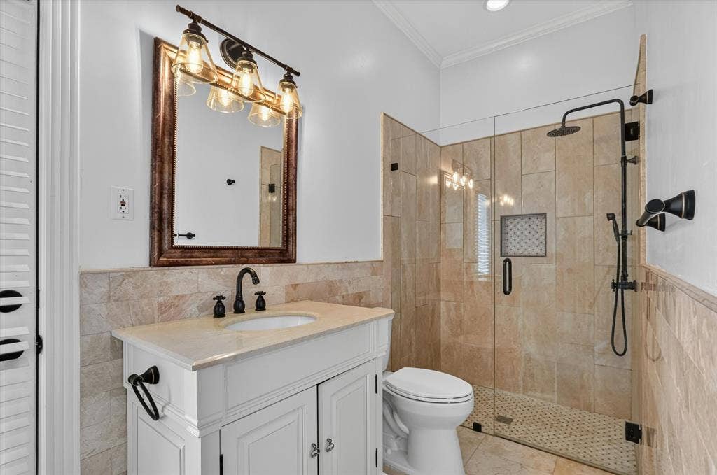 Bathroom featuring a vanity with an undermount sink, a glass-enclosed shower with a rain showerhead, and tile flooring