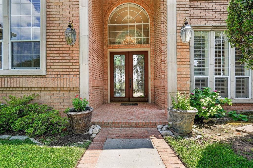 Brick facade entry with an arched double door, transom window, and prominent sidelights