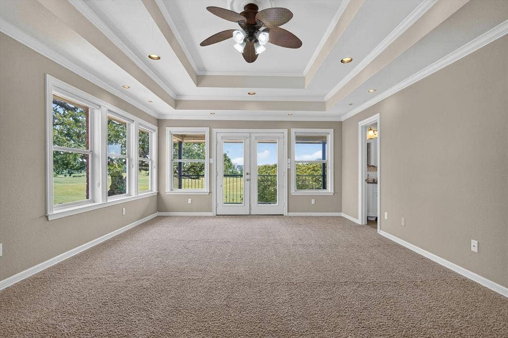Spacious room featuring a tray ceiling with recessed lighting and a ceiling fan