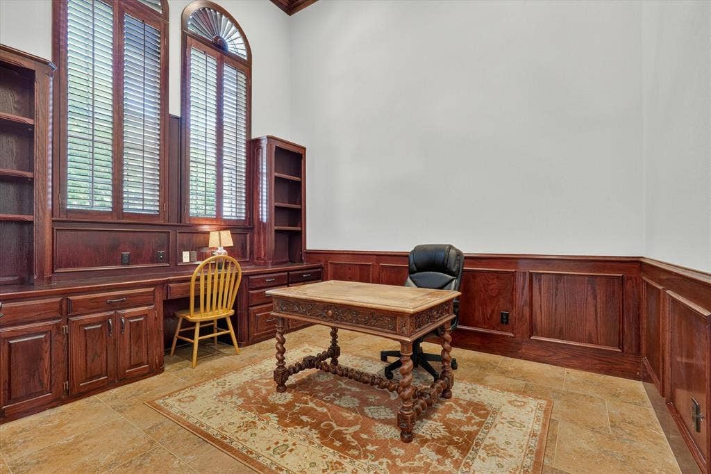 Integrated wood cabinetry with tall arched windows featuring plantation shutters