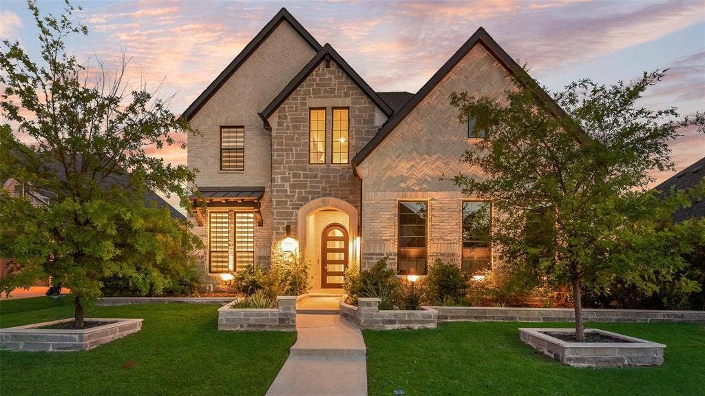 Stone and stucco exterior featuring a prominent arched entryway and dark trim accents