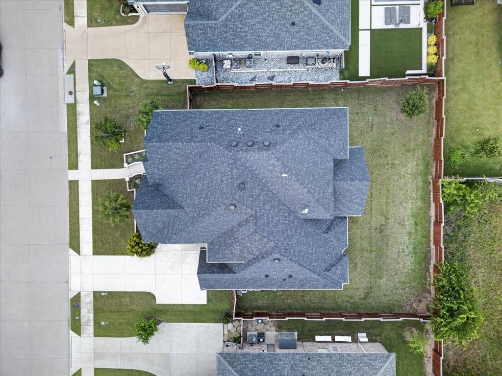 Property with a shingle roof, concrete driveway, and a fenced backyard