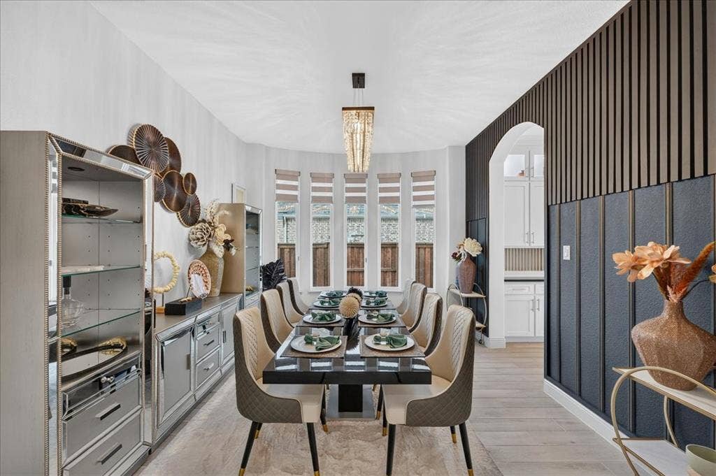 Dining area featuring a contemporary chandelier, a bay window with blinds, and wood-finish flooring