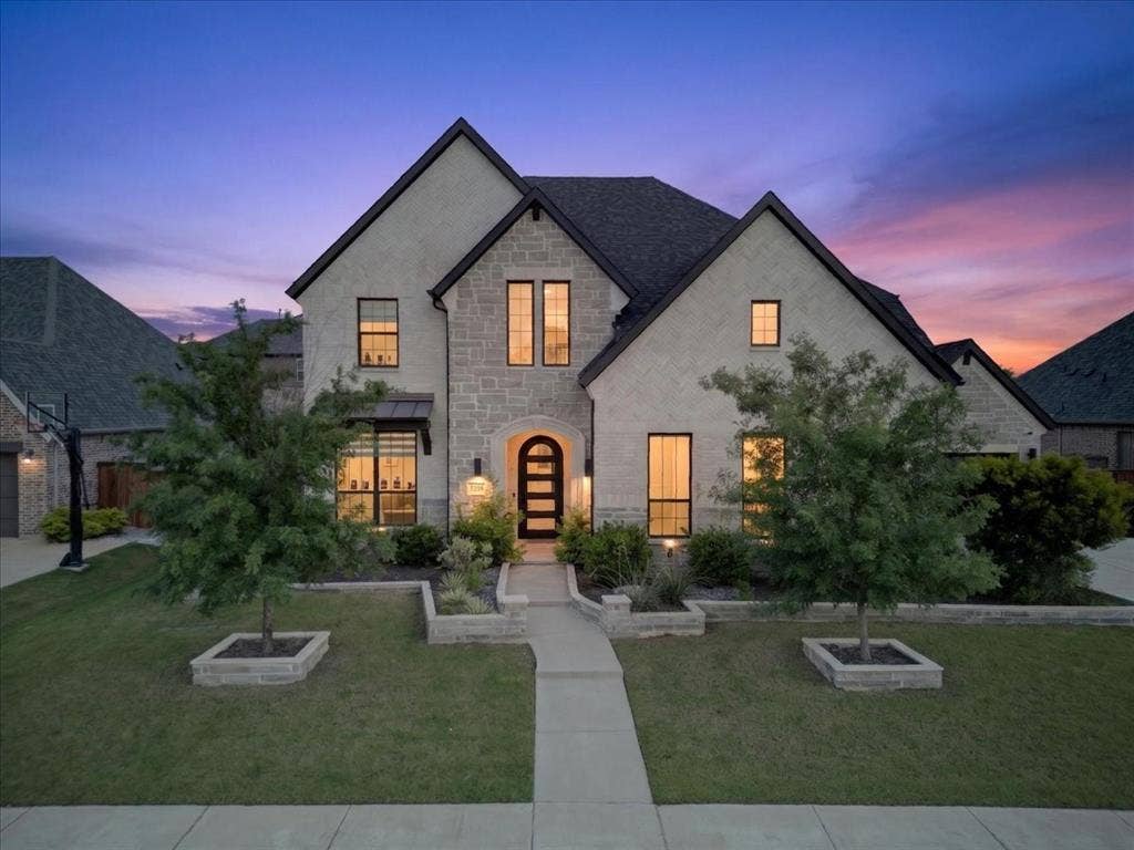 Stately two-story residence featuring a stone and brick façade, dark shingle roof, and multiple gables