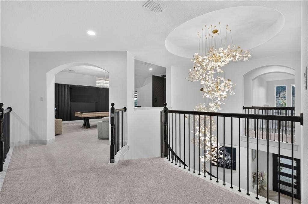 Upper-level landing featuring a grand spiral chandelier suspended from a recessed dome ceiling