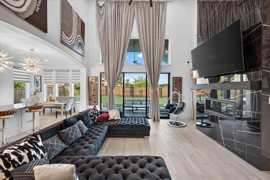 Great room featuring soaring ceilings, a full-height fireplace with polished stone surround, and wood-finish flooring