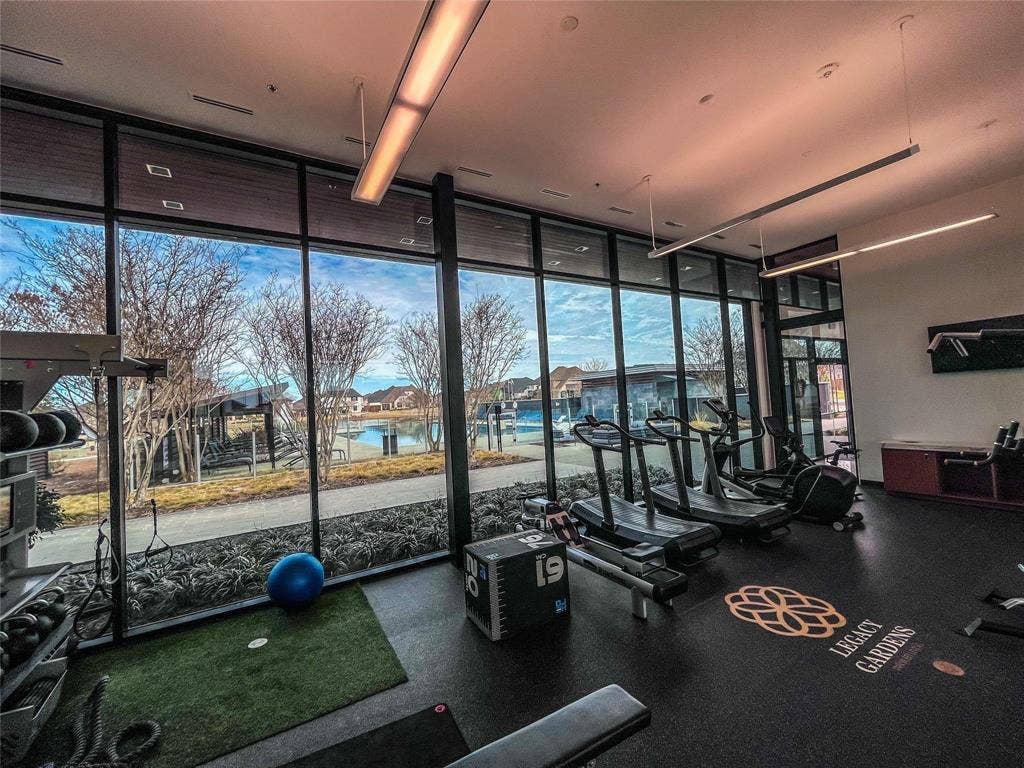 Fitness area featuring floor-to-ceiling windows, a rubberized floor, and linear pendant lighting