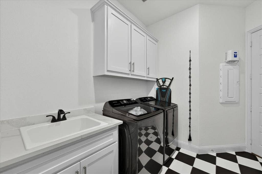 Laundry area featuring a utility sink with a matte black faucet, white shaker-style cabinetry, and striking black and white checkered flooring