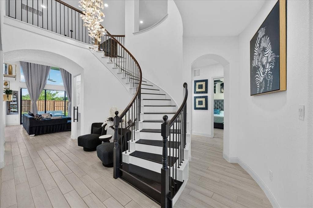 Grand foyer featuring a curved staircase with dark wood treads and wrought iron balusters
