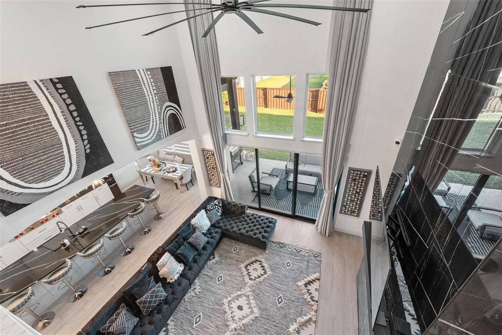 Two-story living area featuring high ceilings, a modern ceiling fan, and large windows with backyard views
