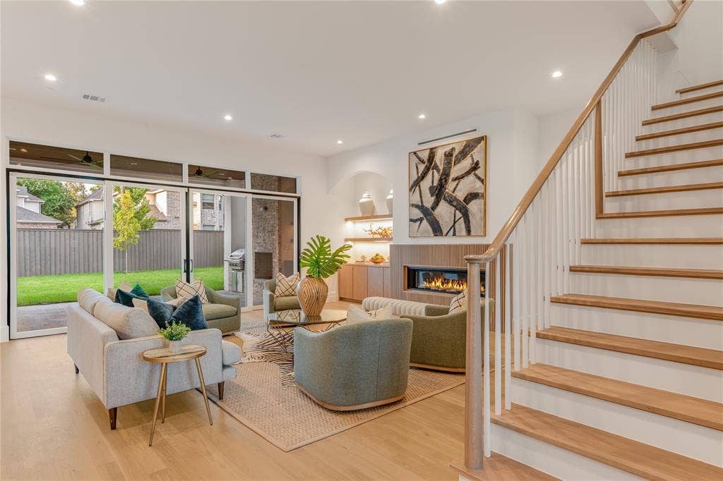 Wood-finish flooring, recessed lighting, built-in fireplace, sliding glass doors, and a wood-finish staircase with white risers