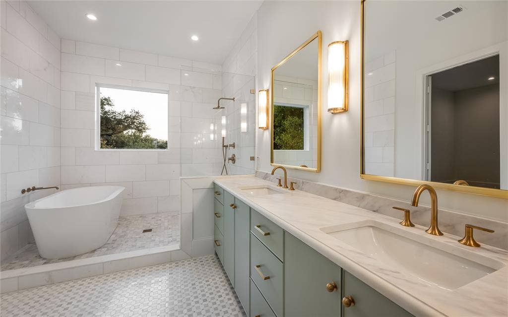 Freestanding soaking tub, walk-in shower with rain head and handheld fixtures, dual vanity with undermount sinks, gold-finish hardware, and marble-finish countertops