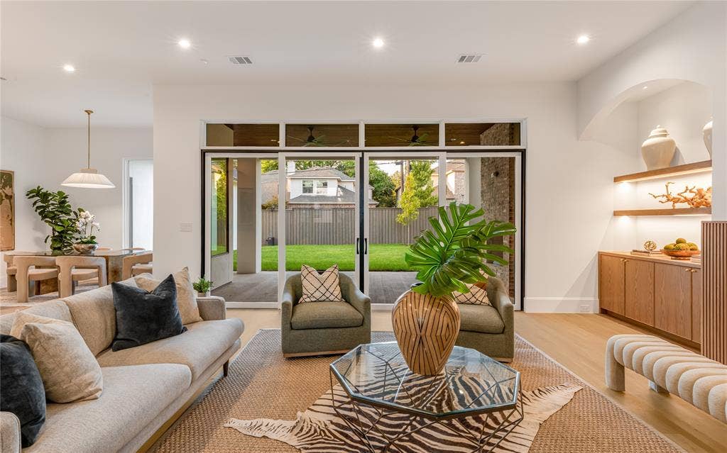 Recessed lighting illuminates the living space with wood-finish flooring