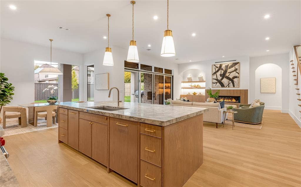 Spacious open-concept living area featuring a large kitchen island with a stone countertop, light wood-finish flooring, and recessed lighting