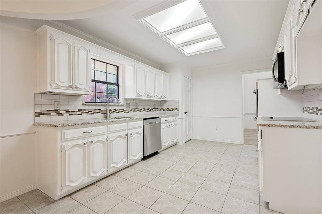 Kitchen featuring white cabinetry, granite countertops, subway tile backsplash with decorative accents, stainless steel dishwasher, and tiled flooring