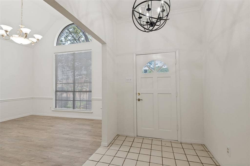 Entryway featuring a white paneled door with an arched glass insert, contemporary spherical chandelier, and square tile flooring