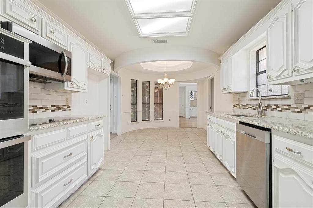 Spacious kitchen featuring white cabinetry, light-toned countertops, and stainless steel appliances