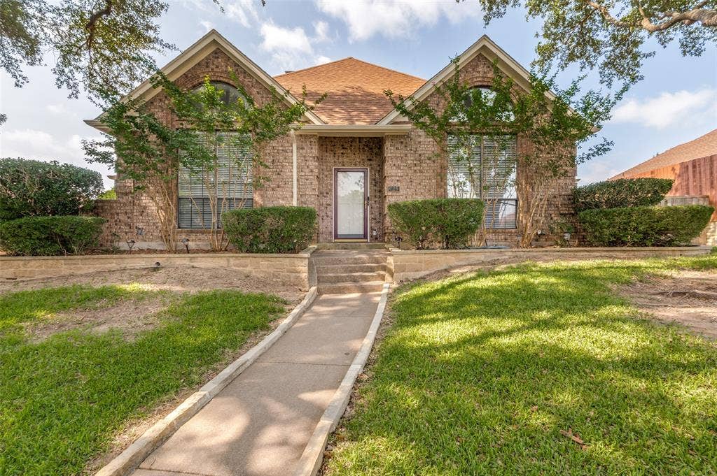 Brick facade residence featuring a front entry with transom window, gabled roofline, and arched window accents