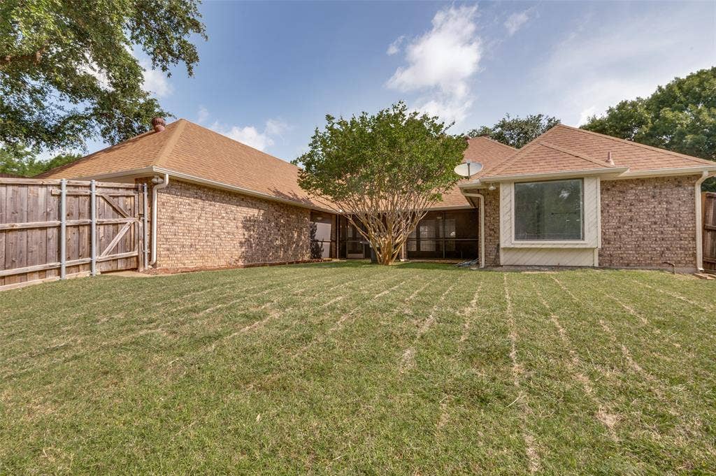 Expansive backyard featuring a manicured lawn, brick exterior, bay window, and privacy fencing