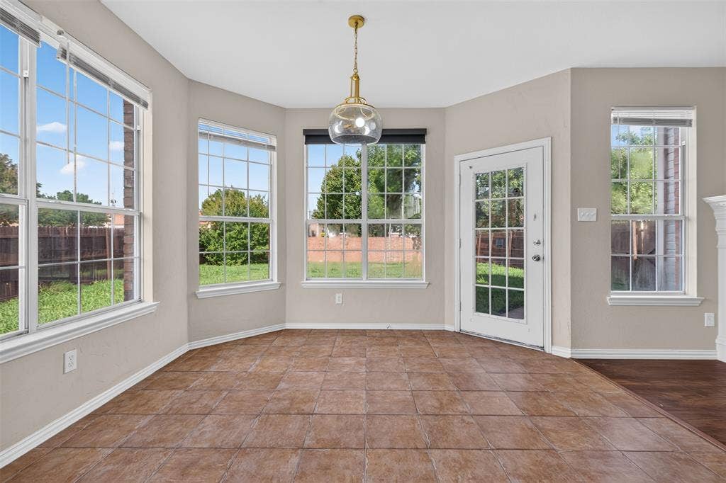 7112 Chandler Drive, Plano, TX 75024 Dining area featuring expansive windows, a glass-paned exterior door, and a modern brass and glass pendant light