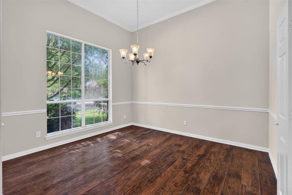 7112 Chandler Drive, Plano, TX 75024 Spacious room featuring wood-finish flooring, a large window with grid panes, crown molding, chair rail molding, and a five-light chandelier