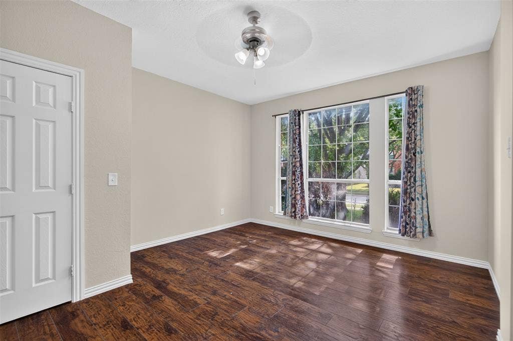 7112 Chandler Drive, Plano, TX 75024 Spacious room featuring rich wood-finish flooring, neutral wall tones, and white baseboards