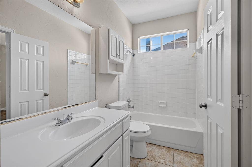 7112 Chandler Drive, Plano, TX 75024 Bathroom featuring a white vanity with integrated sink, chrome faucet, and expansive mirror
