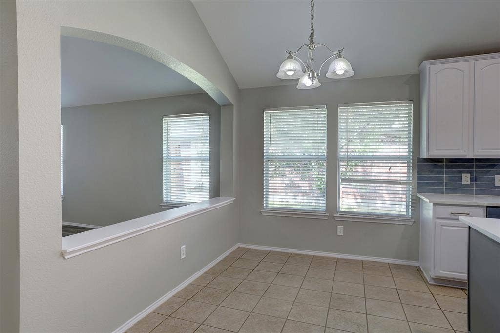 1214 Cedar Branch Drive, Wylie, TX 75098 Open-concept dining area featuring tile flooring, a contemporary chandelier, and a pass-through arched opening to an adjacent space