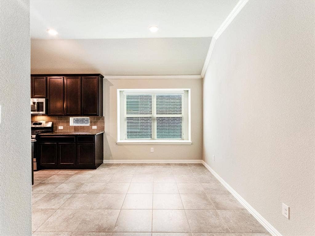 Kitchen area featuring dark wood-finish cabinetry, a ceramic tile backsplash, and stainless steel appliances