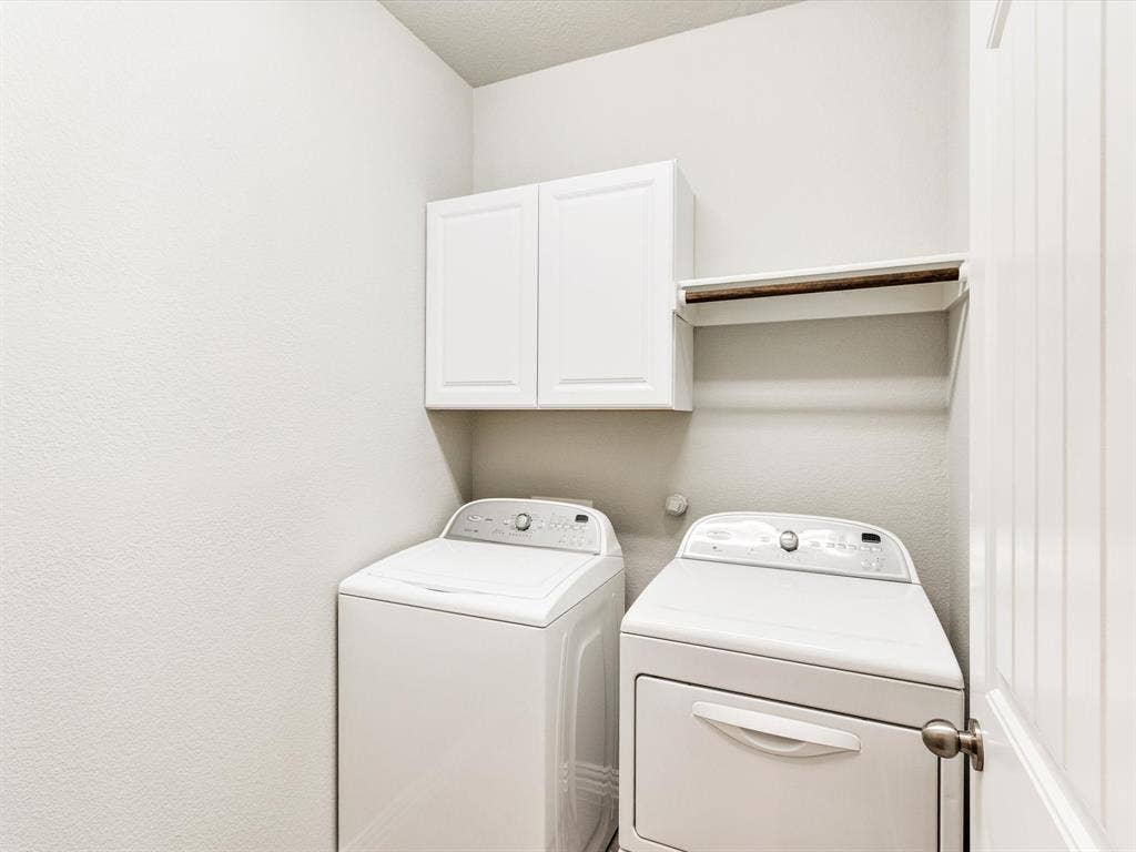 Dedicated laundry area featuring a white shaker-style wall cabinet and a built-in shelf