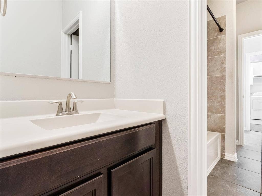 Bathroom vanity with a white countertop and integrated sink, brushed nickel faucet hardware, and dark wood-finish cabinetry