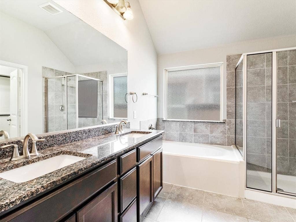 Bathroom featuring a dual vanity with granite-finish countertop, dark wood-finish cabinetry, and brushed nickel fixtures