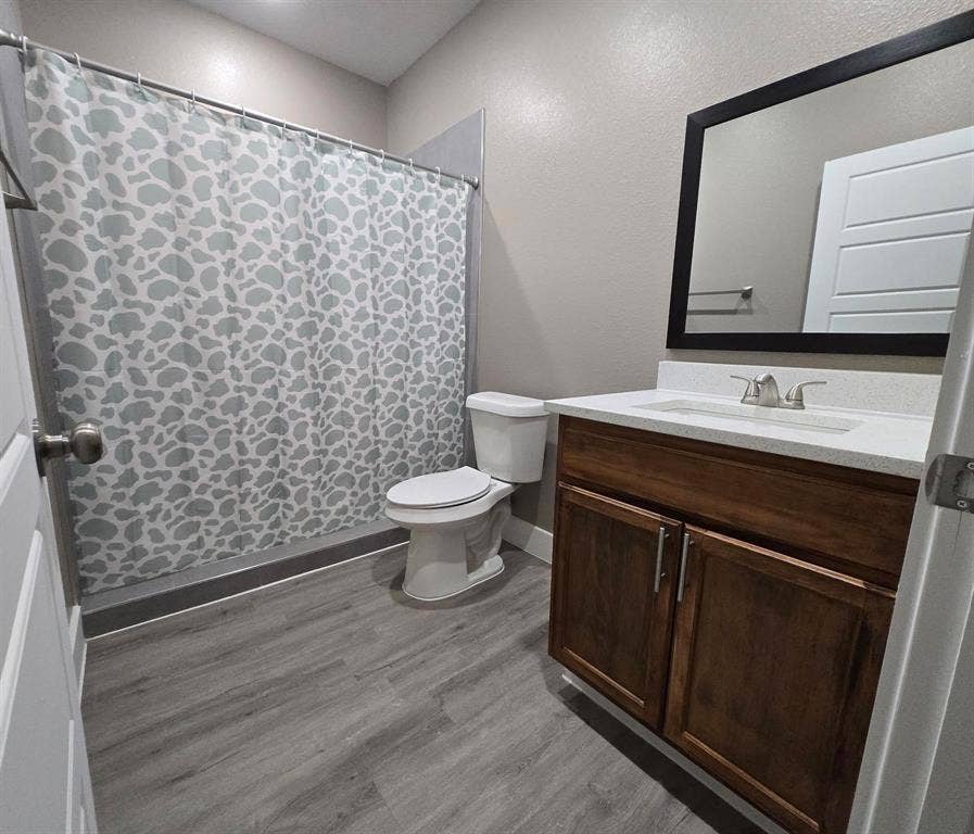 3513 Tomahawk Drive, Granbury, TX 76048 Bathroom featuring a wood-finish vanity with a light-toned countertop, an integrated sink, and a framed mirror