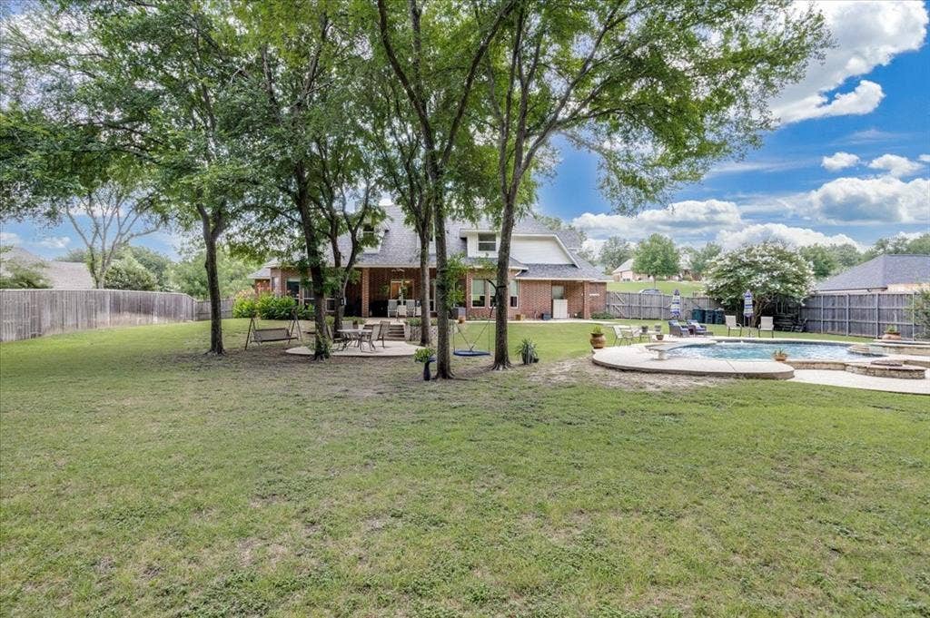 Expansive backyard featuring a large in-ground swimming pool, a concrete patio, and a privacy fence