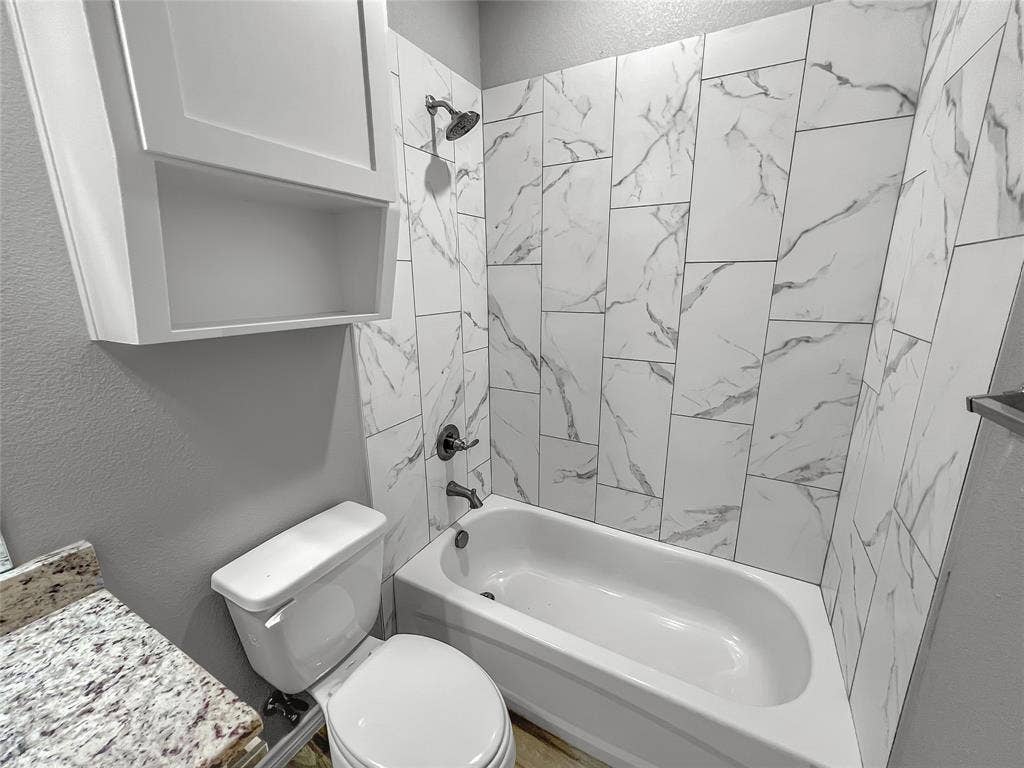 1210 Campbelton Drive, Temple, TX 76504 Bathroom featuring a white porcelain bathtub, wall-mounted showerhead, and tiled surround with a marble-look pattern